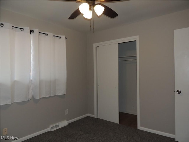 unfurnished bedroom featuring baseboards, visible vents, dark carpet, and a closet