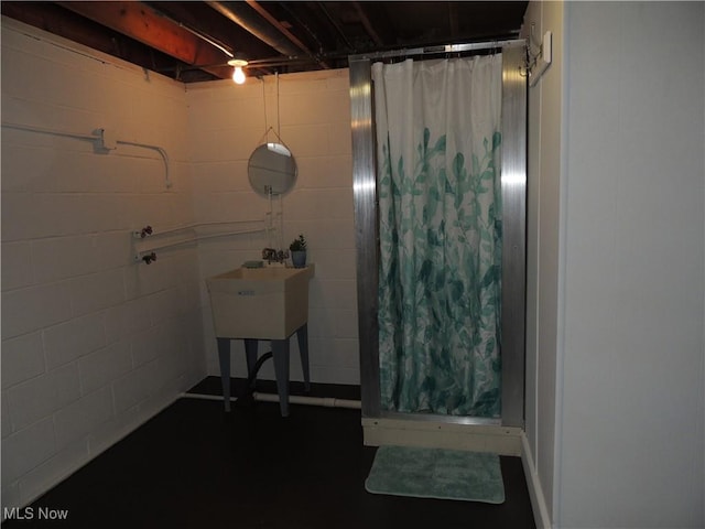 bathroom featuring a shower stall and concrete block wall