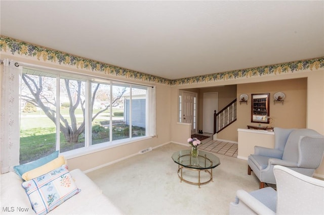 carpeted living room featuring baseboards, a healthy amount of sunlight, stairs, and visible vents
