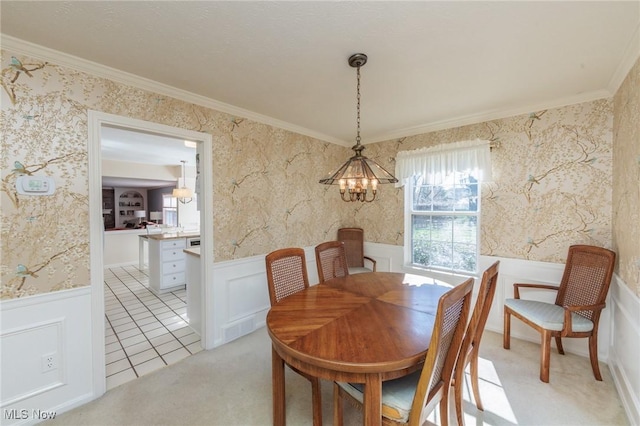 dining room featuring an inviting chandelier, ornamental molding, a wainscoted wall, and wallpapered walls