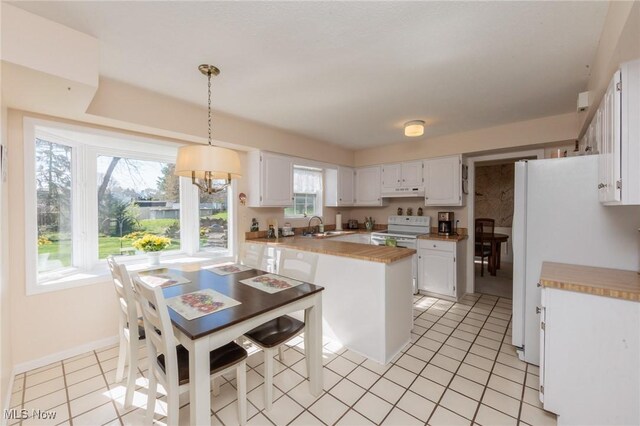 kitchen featuring under cabinet range hood, light countertops, a sink, white appliances, and white cabinetry