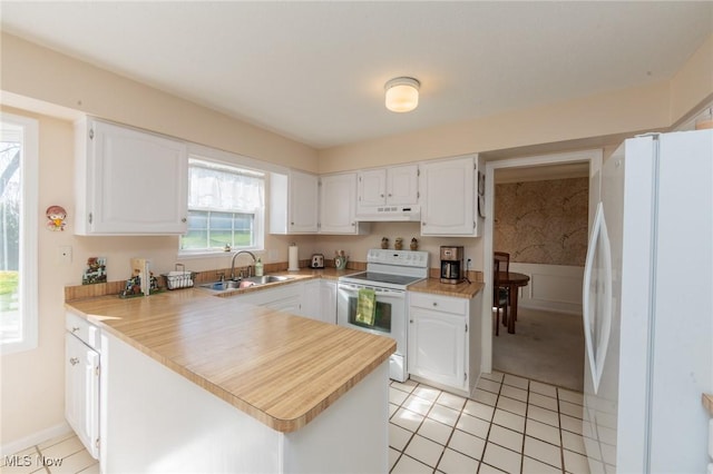 kitchen featuring under cabinet range hood, light tile patterned floors, a sink, and white appliances