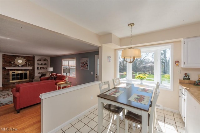 dining room featuring a fireplace, plenty of natural light, built in features, and baseboards