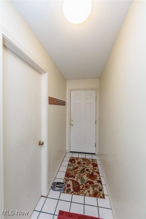 doorway with light tile patterned flooring and baseboards