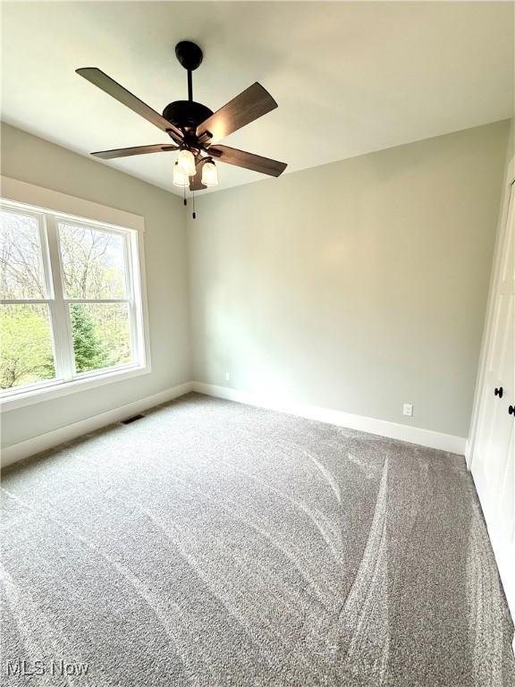 carpeted spare room with baseboards and ceiling fan