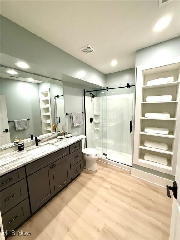 bathroom featuring a shower stall, wood finished floors, vanity, toilet, and visible vents