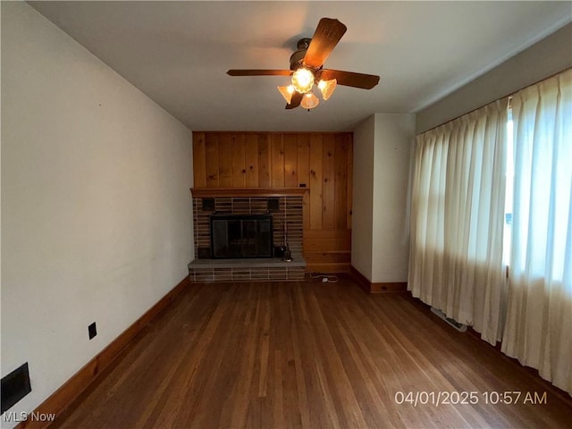 224 E Pine St, Lisbon, OH 44432 - unfurnished living room featuring baseboards, wood finished floors, ceiling fan, wooden walls, and a fireplace
