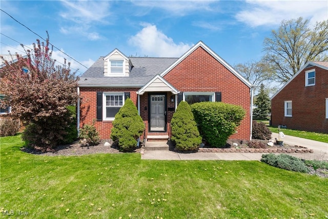 view of front of property featuring a shingled roof, a front lawn, and brick siding