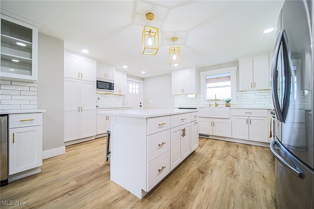 kitchen featuring a center island, light wood-style flooring, built in microwave, tasteful backsplash, and freestanding refrigerator