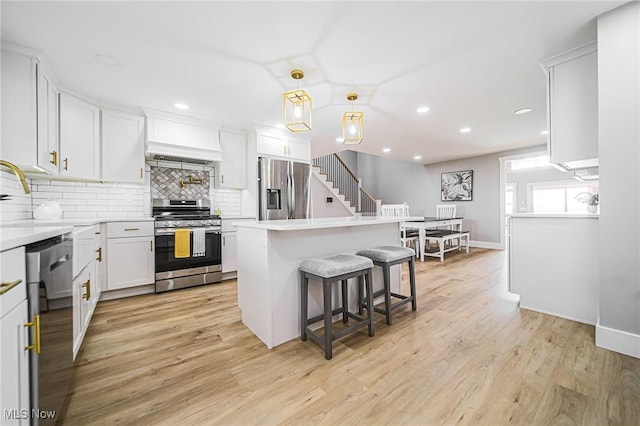 kitchen featuring tasteful backsplash, a breakfast bar, stainless steel appliances, light countertops, and white cabinets