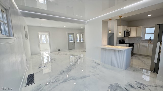 kitchen with stainless steel microwave, a healthy amount of sunlight, visible vents, gas range, and marble finish floor