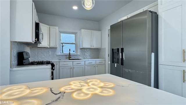 kitchen featuring a sink, decorative backsplash, stainless steel appliances, light countertops, and white cabinets