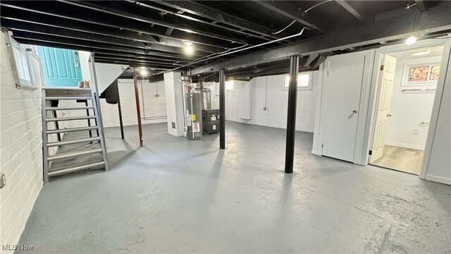 below grade area featuring concrete block wall and gas water heater
