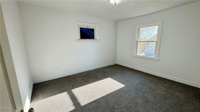 unfurnished room with baseboards and dark colored carpet