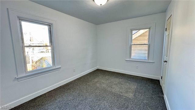 empty room featuring dark carpet and baseboards