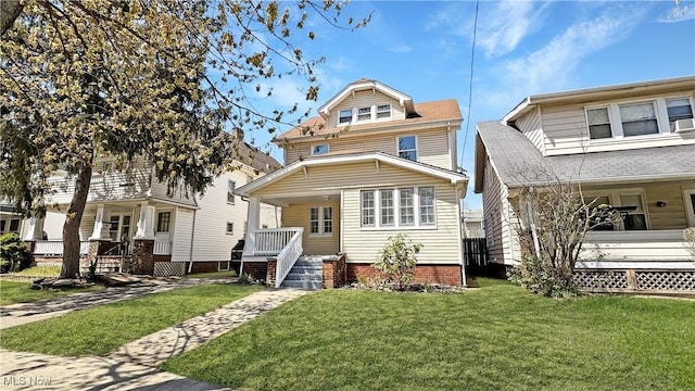 american foursquare style home with a porch and a front lawn