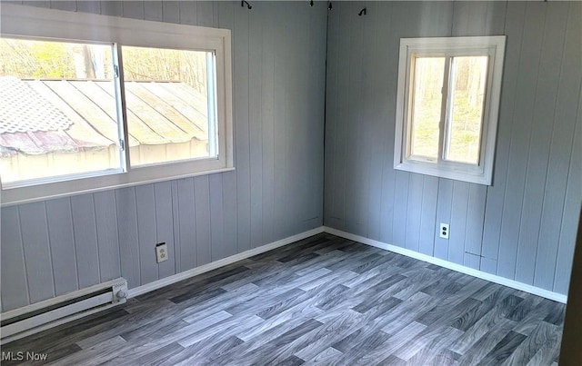 135 Paradise Blvd, Madison, OH 44057 - empty room with a baseboard heating unit, wooden walls, wood finished floors, and baseboards