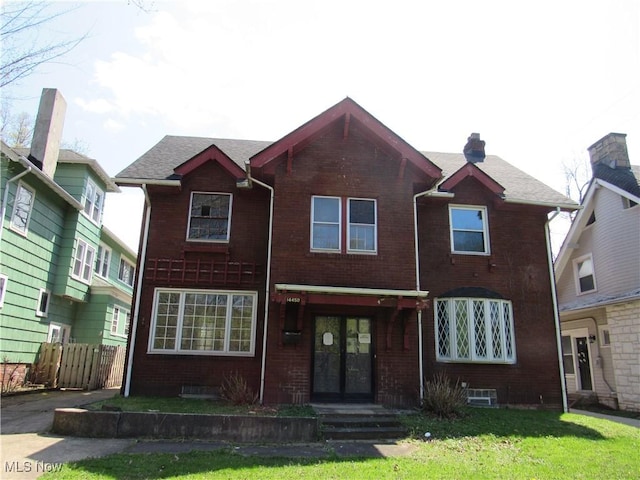 view of front of property featuring brick siding, fence, french doors, and a front yard