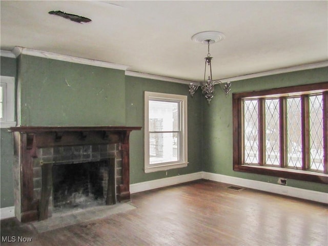 unfurnished living room featuring plenty of natural light, wood finished floors, baseboards, and ornamental molding