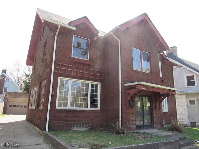view of front of property featuring an outdoor structure, driveway, brick siding, and a garage