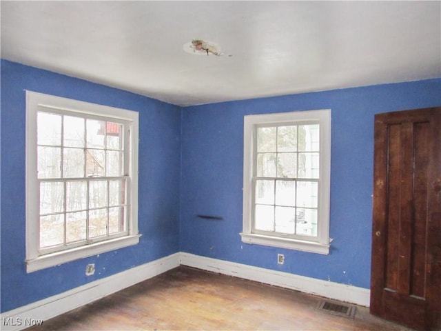 unfurnished room with plenty of natural light, baseboards, and wood finished floors