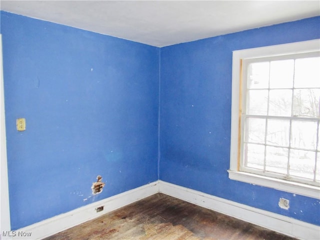 empty room with baseboards, a wealth of natural light, and dark wood-style floors
