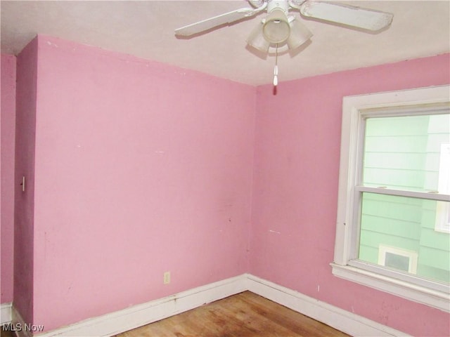 empty room featuring wood finished floors, a ceiling fan, and baseboards