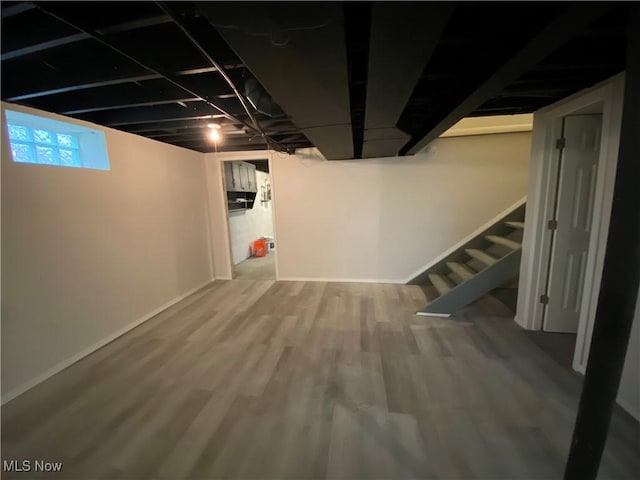 below grade area with stairway, baseboards, and wood finished floors