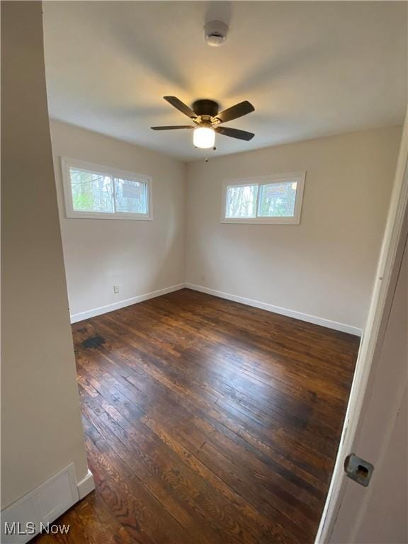 unfurnished room featuring a ceiling fan, baseboards, and dark wood-style flooring