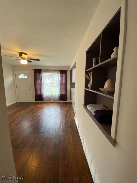 unfurnished living room with hardwood / wood-style flooring, baseboards, and a ceiling fan