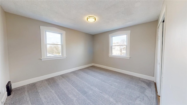 unfurnished room with carpet floors, a textured ceiling, and baseboards