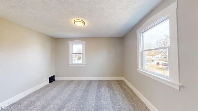 carpeted empty room featuring baseboards and a textured ceiling