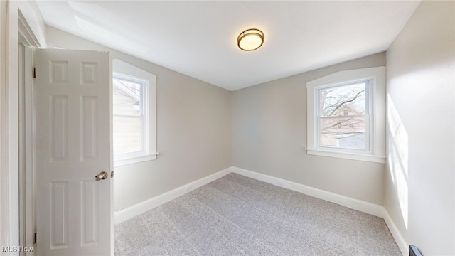 empty room featuring a wealth of natural light, baseboards, and carpet