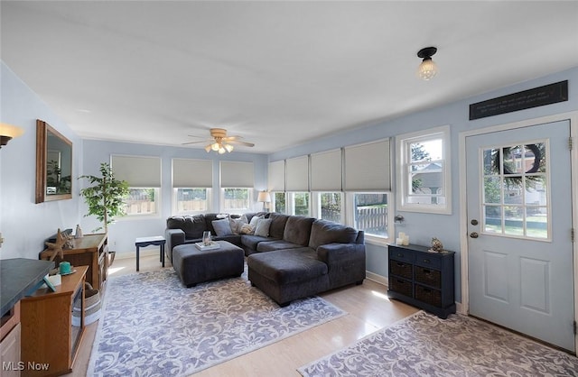 living room with light wood-type flooring, ceiling fan, and a healthy amount of sunlight