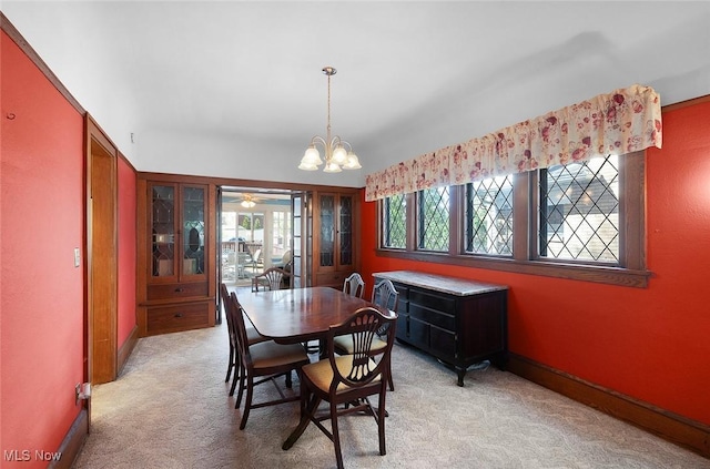 dining space with baseboards, light carpet, and ceiling fan with notable chandelier