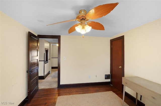 empty room featuring baseboards, a ceiling fan, visible vents, and dark wood-type flooring