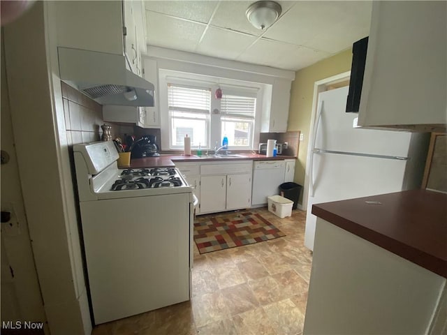 kitchen featuring a drop ceiling, under cabinet range hood, white appliances, decorative backsplash, and white cabinetry
