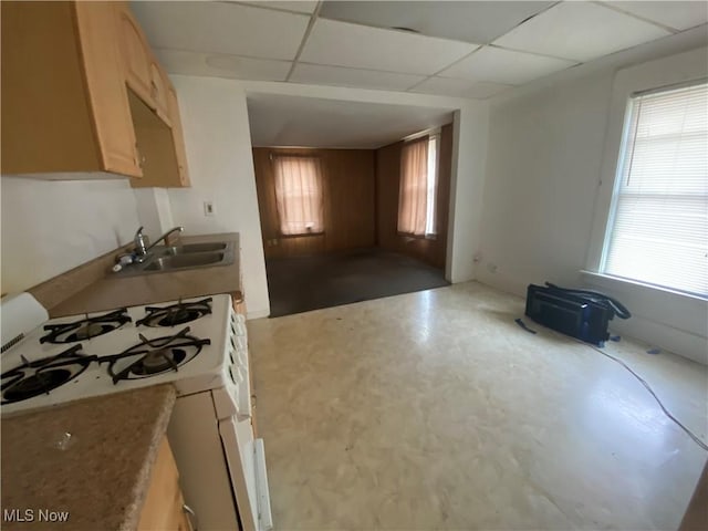 kitchen with light brown cabinets, white gas range, a sink, and a drop ceiling