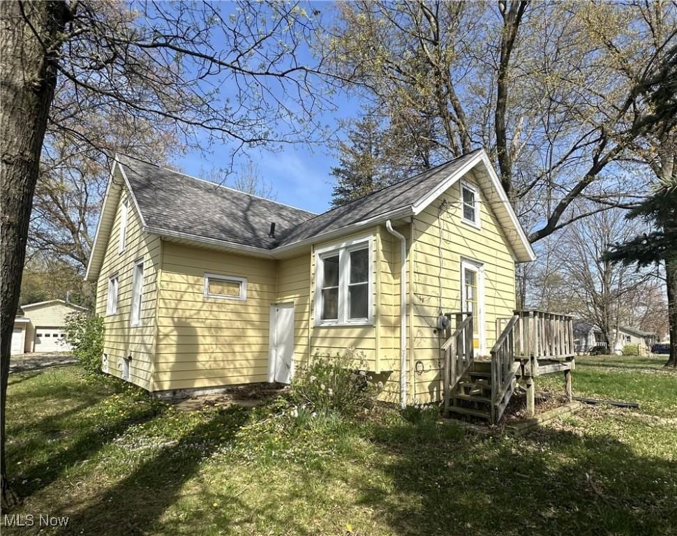 exterior space featuring a yard, a shingled roof, and a deck