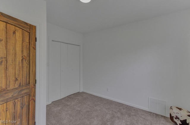 unfurnished bedroom with a closet, carpet, visible vents, and baseboards