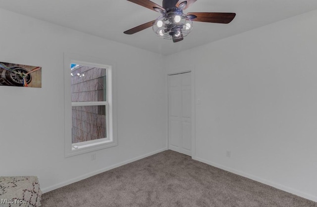carpeted empty room with a ceiling fan and baseboards