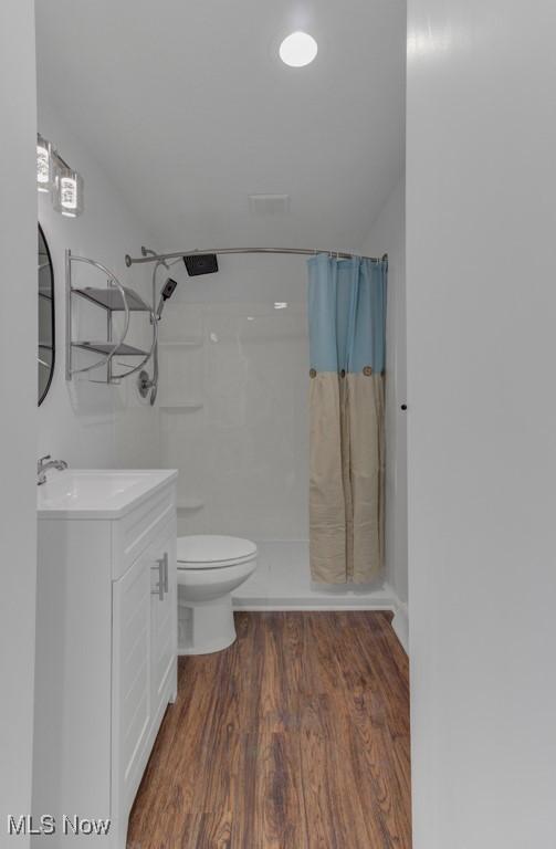 bathroom with vanity, toilet, wood finished floors, and a shower with shower curtain