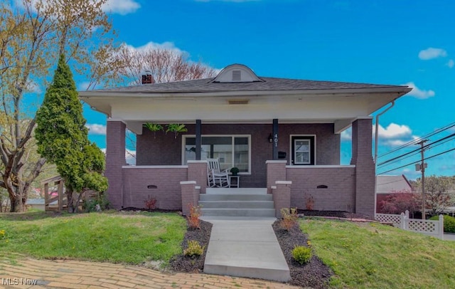 bungalow-style home with brick siding, a porch, a front yard, and fence