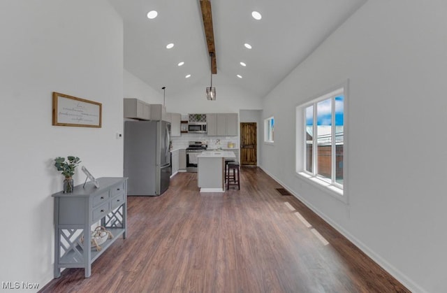kitchen with a kitchen breakfast bar, stainless steel appliances, dark wood-type flooring, lofted ceiling with beams, and gray cabinetry