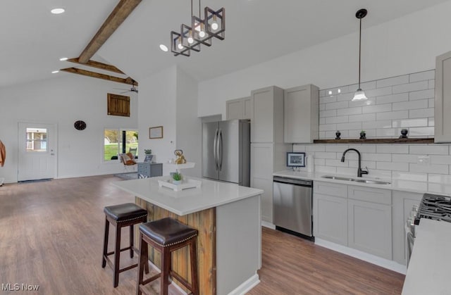 kitchen with light countertops, a sink, beamed ceiling, tasteful backsplash, and appliances with stainless steel finishes