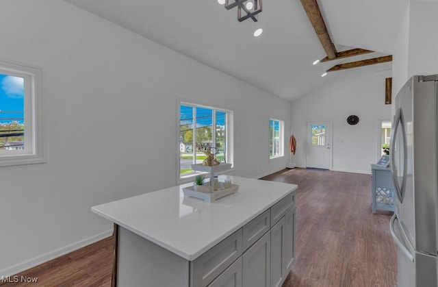 kitchen featuring beamed ceiling, freestanding refrigerator, dark wood-type flooring, a kitchen island, and gray cabinetry