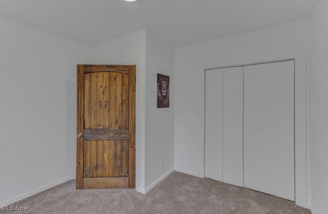 unfurnished bedroom with baseboards, carpet flooring, and a closet