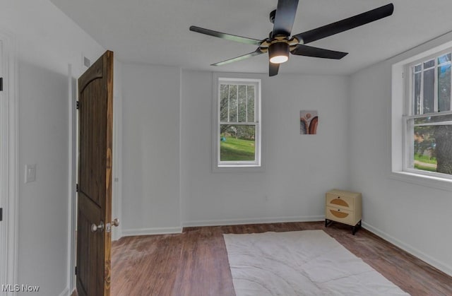 unfurnished room with baseboards, a ceiling fan, and wood finished floors