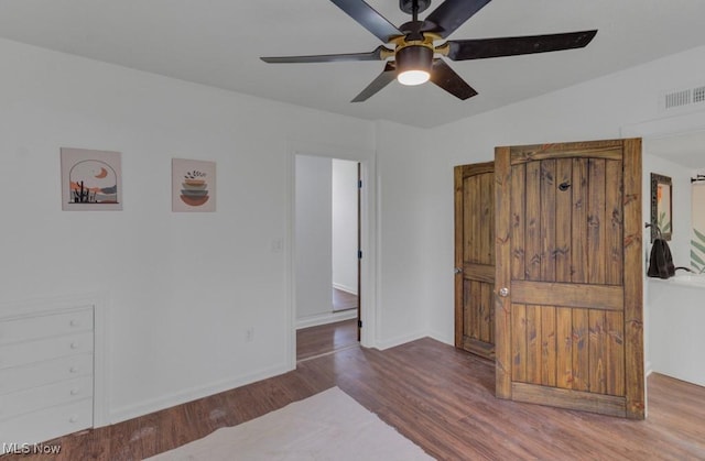 unfurnished room with baseboards, wood finished floors, visible vents, and a ceiling fan