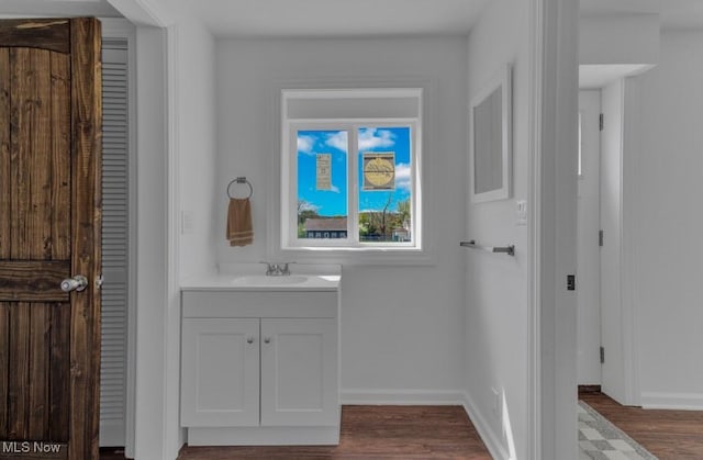 bathroom with wood finished floors, vanity, and baseboards